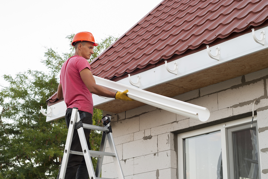 worker installs the gutter system on the roof