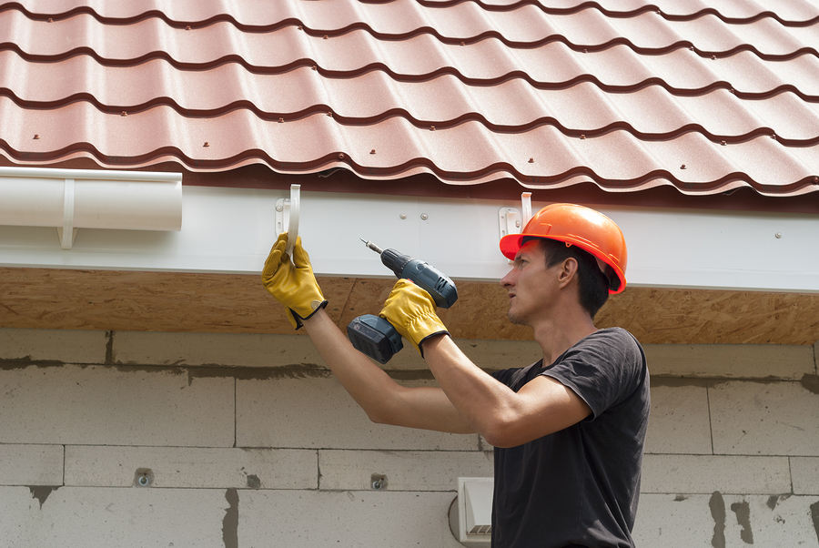 man installs the gutter system on the roof