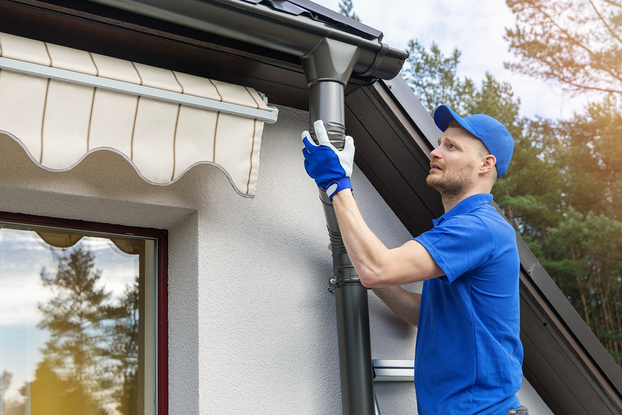 worker installing house roof rain gutter system